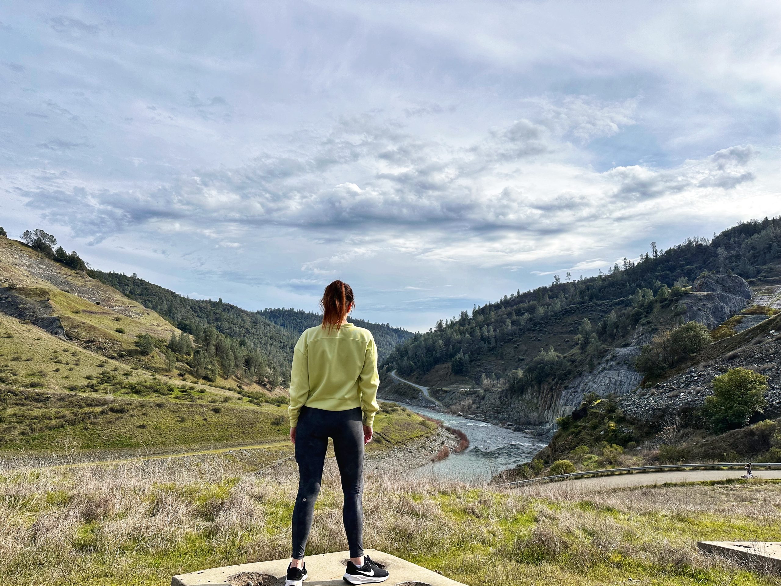 Woman looking out over a river and mountains, symbolizing reflection and growth after leaving Mormonism
