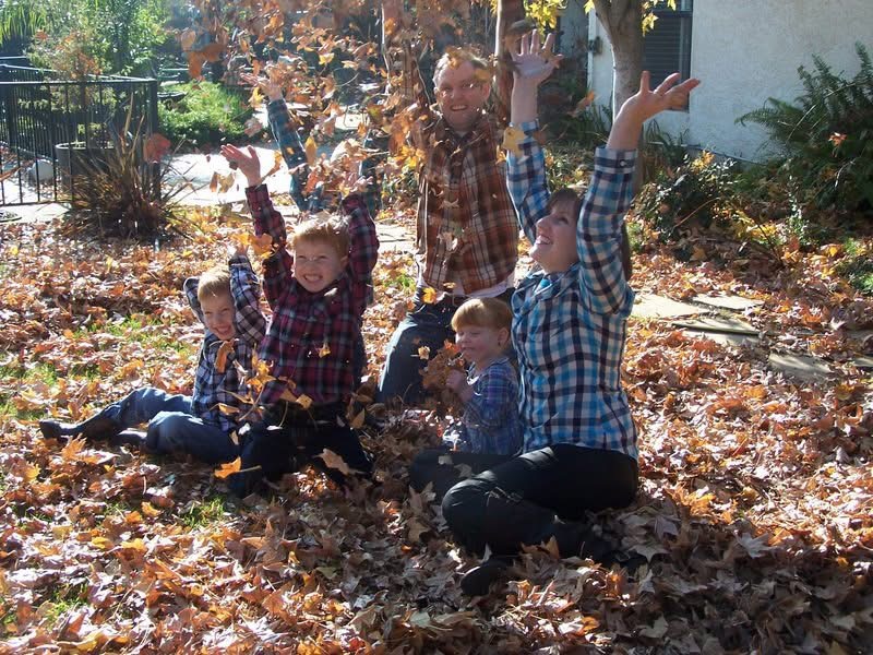 Family playing in autumn leaves, a moment of joy captured during a difficult season.